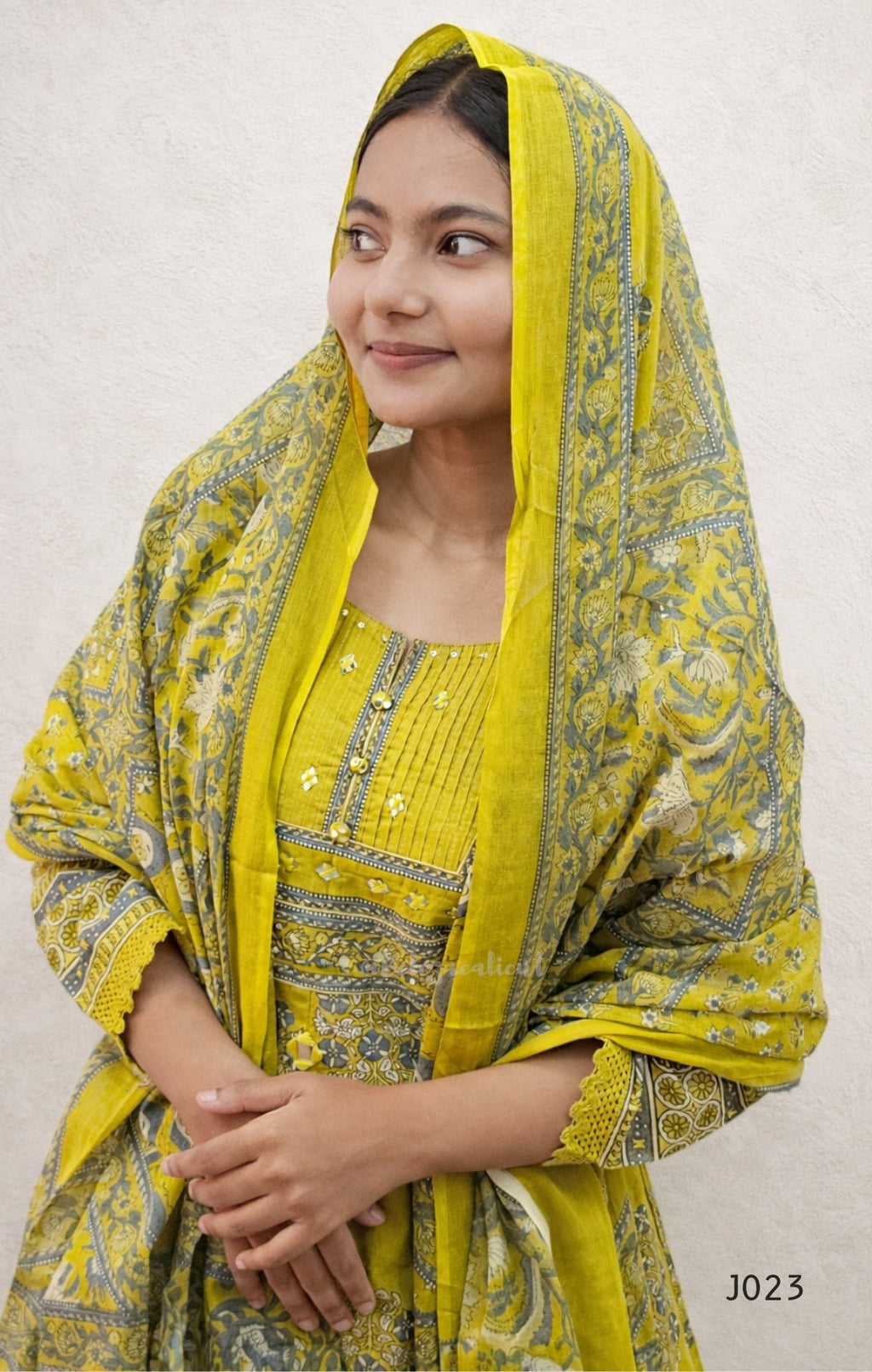 Woman wearing a yellow traditional outfit with a matching dupatta on a white background