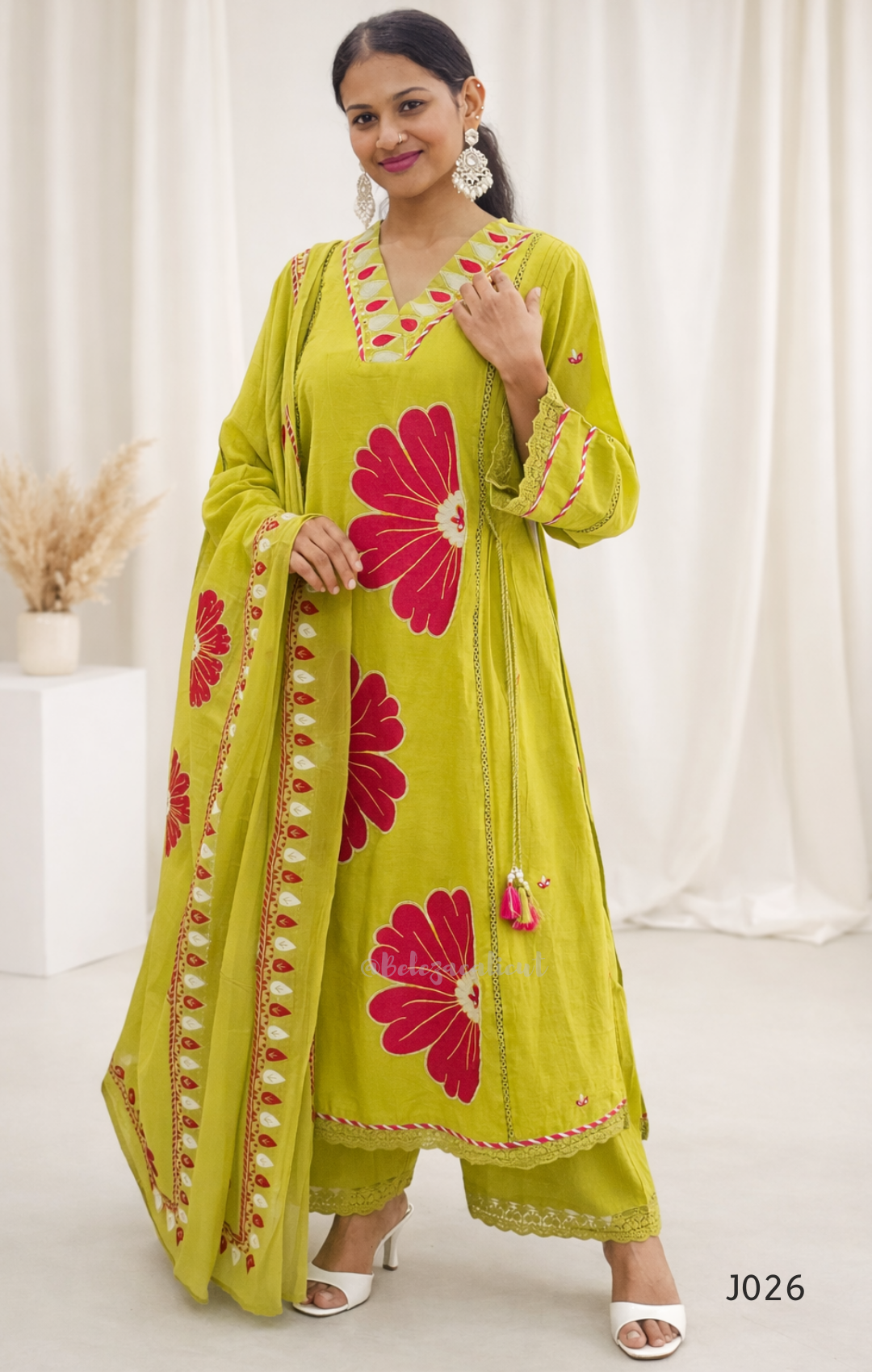 Woman wearing a green dress with pink floral patterns against a white background