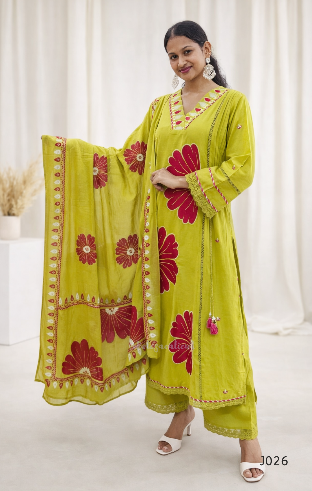 Woman wearing a green and red embroidered traditional outfit with a matching dupatta.