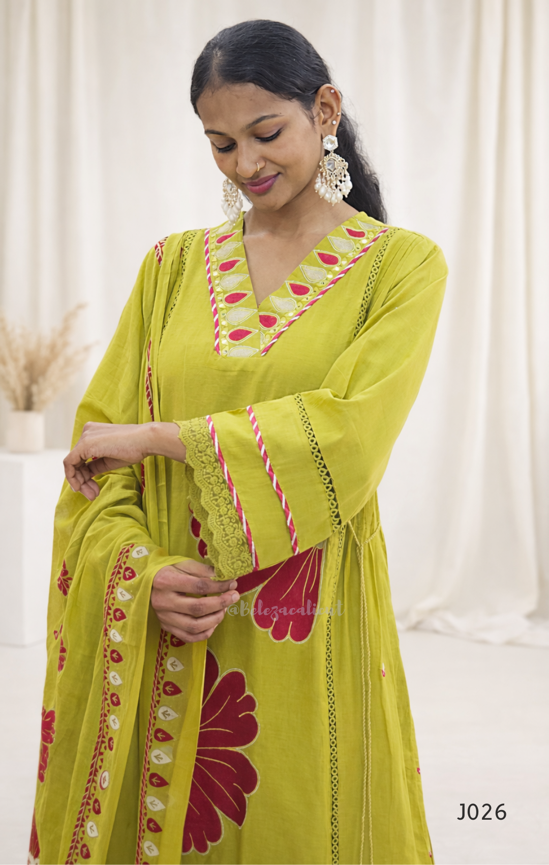 Woman wearing a green embroidered traditional outfit with a white background
