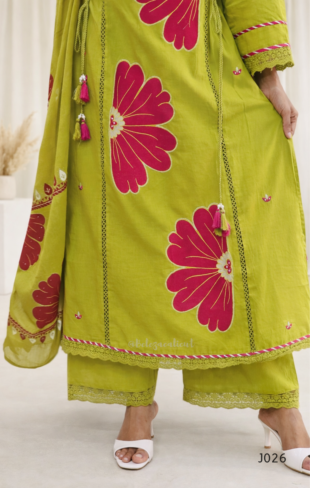 Green traditional outfit with pink floral patterns on a white background