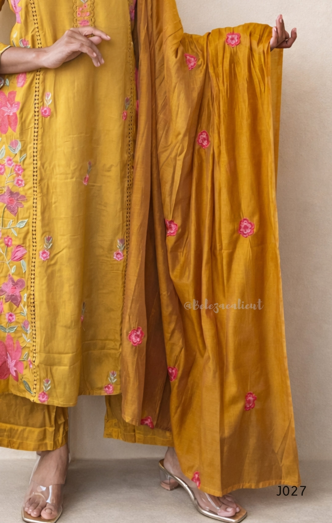 Mustard yellow traditional outfit with floral embroidery on a plain background