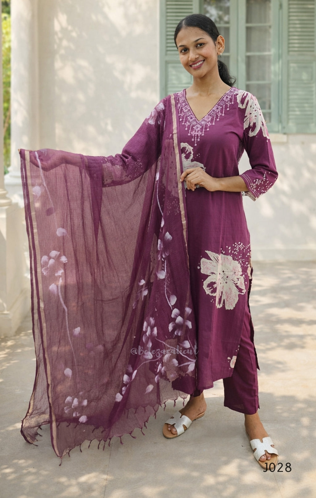 Woman wearing a purple embroidered outfit with a matching dupatta, standing outdoors.