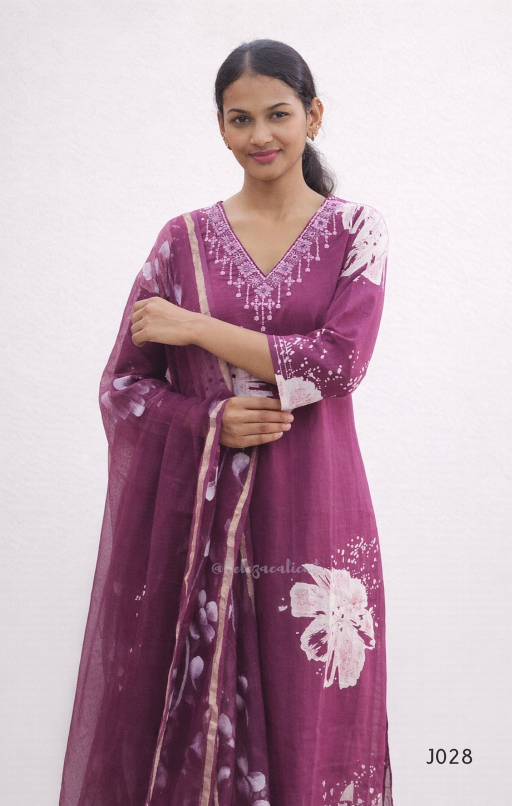 Woman wearing a purple embroidered dress with a matching dupatta on a white background