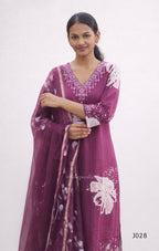 Woman wearing a purple embroidered dress with a matching dupatta on a white background