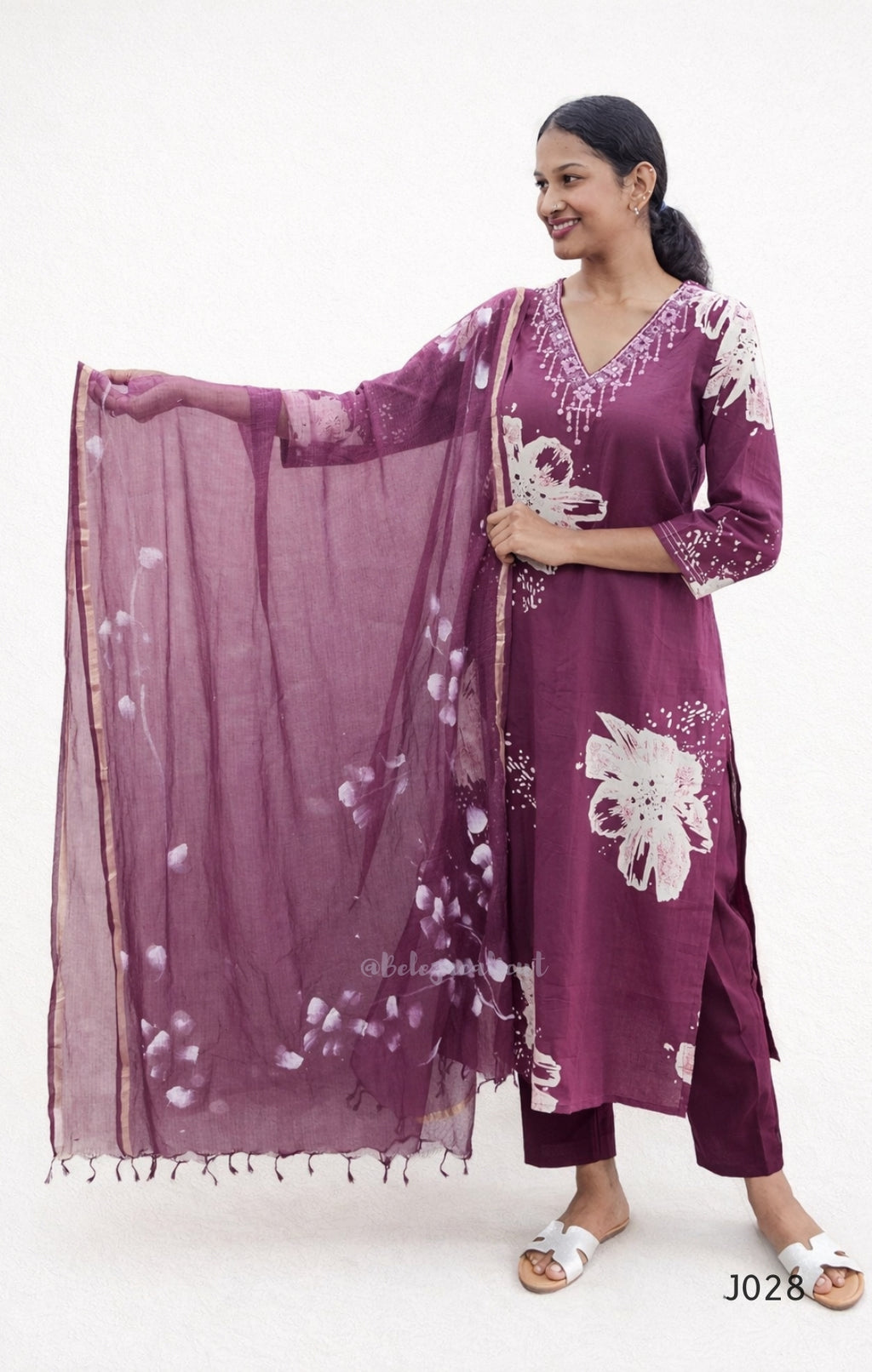 Woman wearing a purple traditional outfit with white floral patterns on a white background