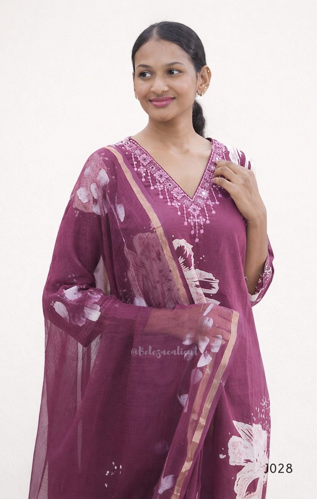 Woman wearing a maroon saree with white floral patterns on a plain background