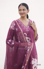 Woman wearing a maroon saree with white floral patterns on a plain background