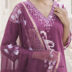 Purple traditional outfit with floral patterns and embellishments on a neutral background