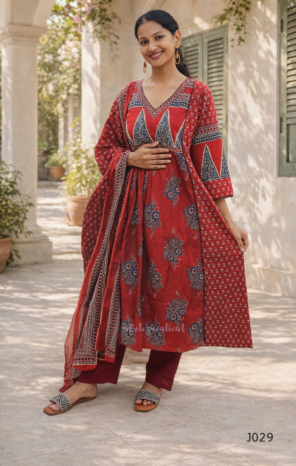 Woman wearing a red and blue patterned outfit standing outdoors.