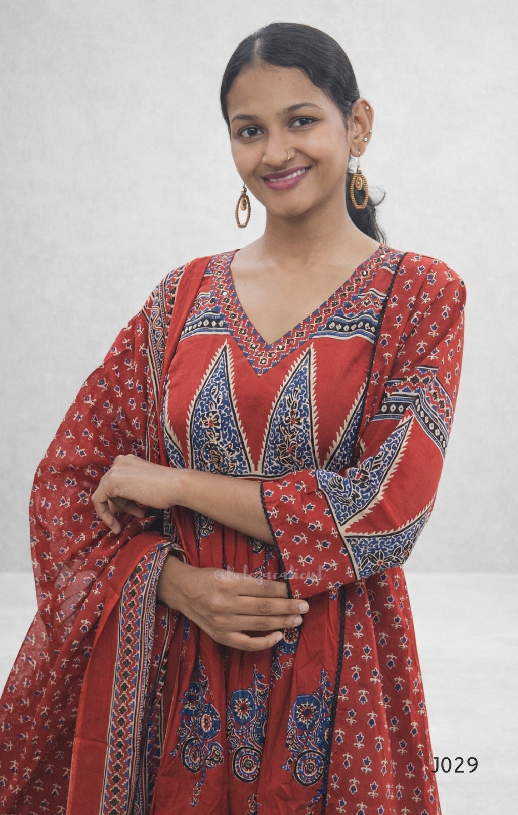 Woman wearing a red patterned dress against a white background