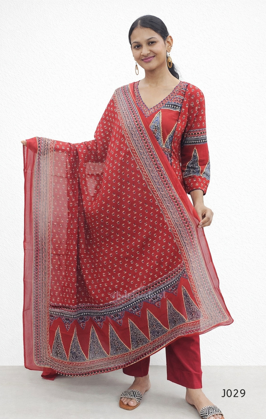 Woman wearing a red traditional outfit with a patterned dupatta on a white background