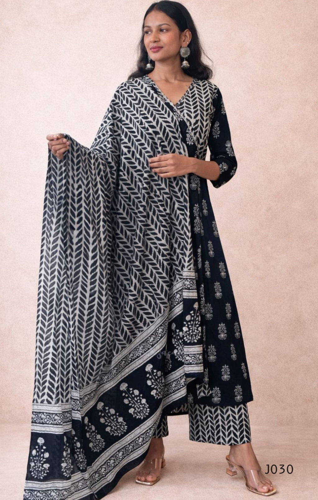 Woman wearing a black and white patterned outfit with a matching dupatta on a beige background