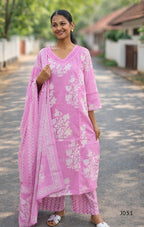 Woman wearing a pink traditional outfit with white floral patterns on a road.