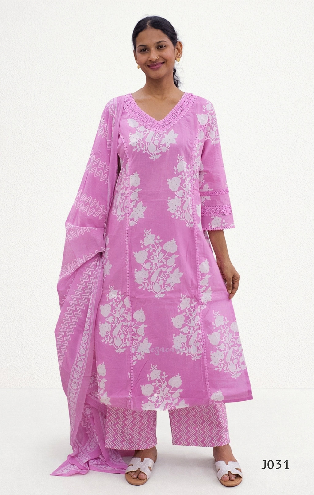 Woman wearing a pink traditional outfit with white floral patterns on a white background
