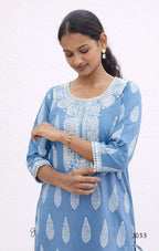 Woman wearing a blue dress with white patterns on a white background