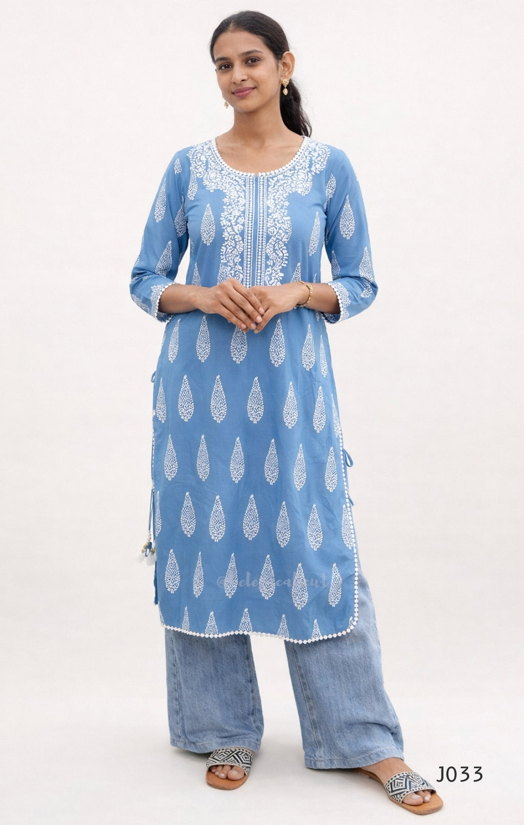 Woman wearing a blue patterned kurta with white embroidery on a white background