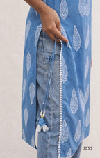 Blue patterned cover-up with white designs over a denim outfit on a light background