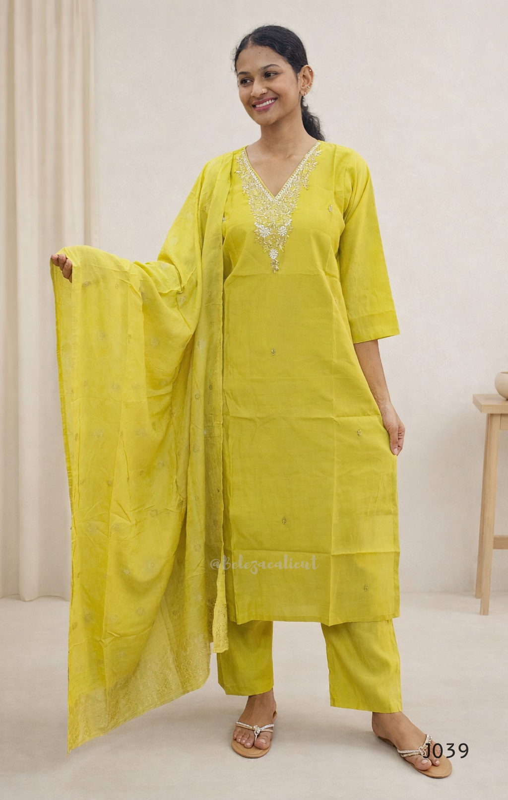 Woman wearing a yellow traditional outfit with a dupatta against a white background