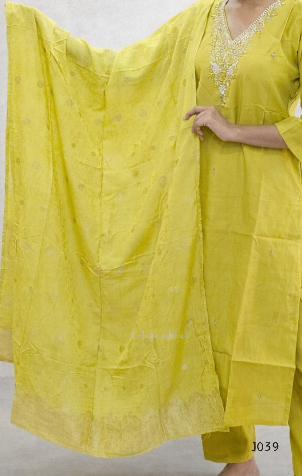 Yellow traditional outfit with intricate patterns on a plain background