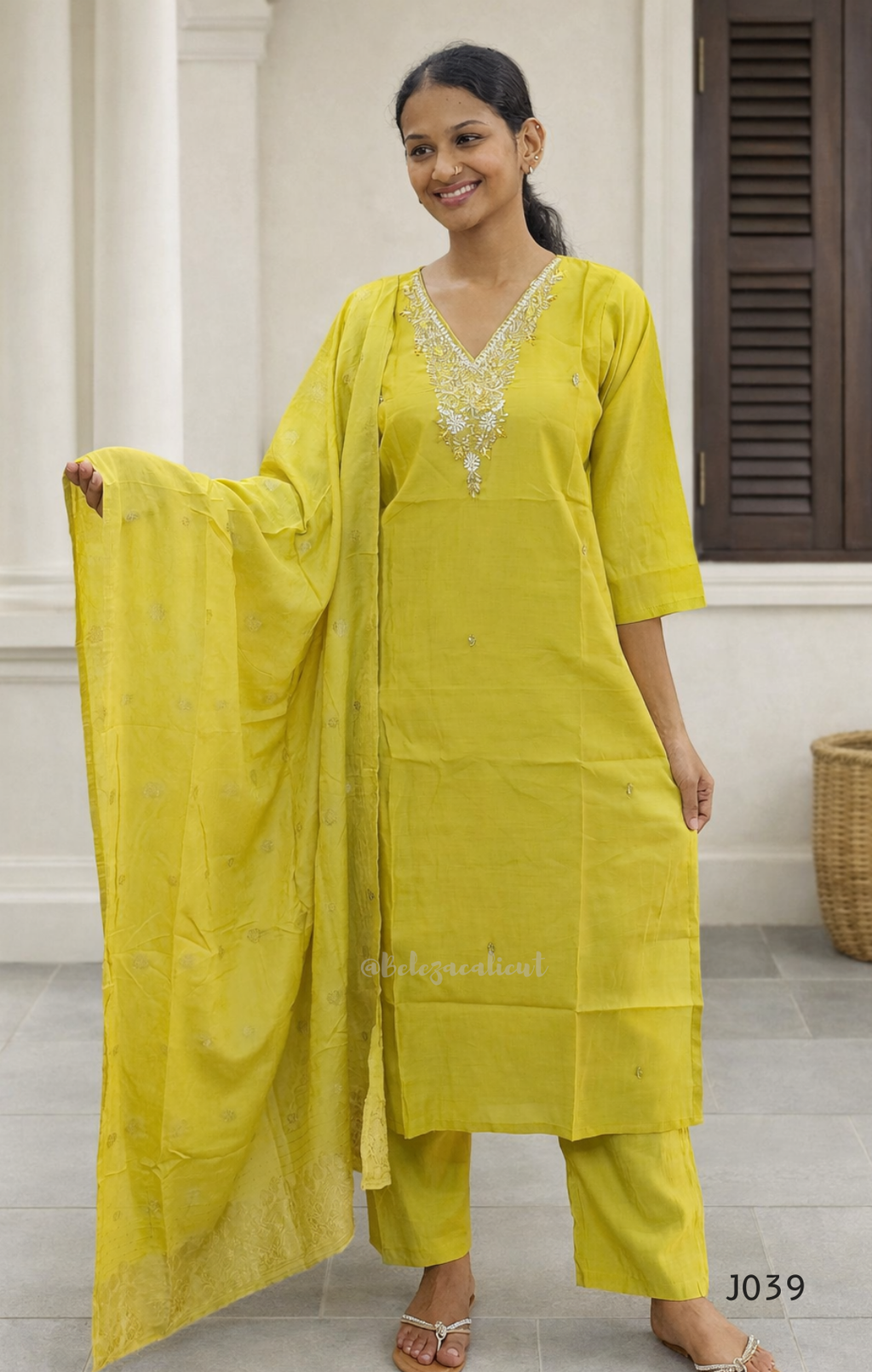 Woman wearing a yellow traditional outfit with a matching dupatta indoors.