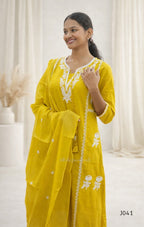 Woman wearing a yellow traditional outfit with white embroidery in a neutral setting