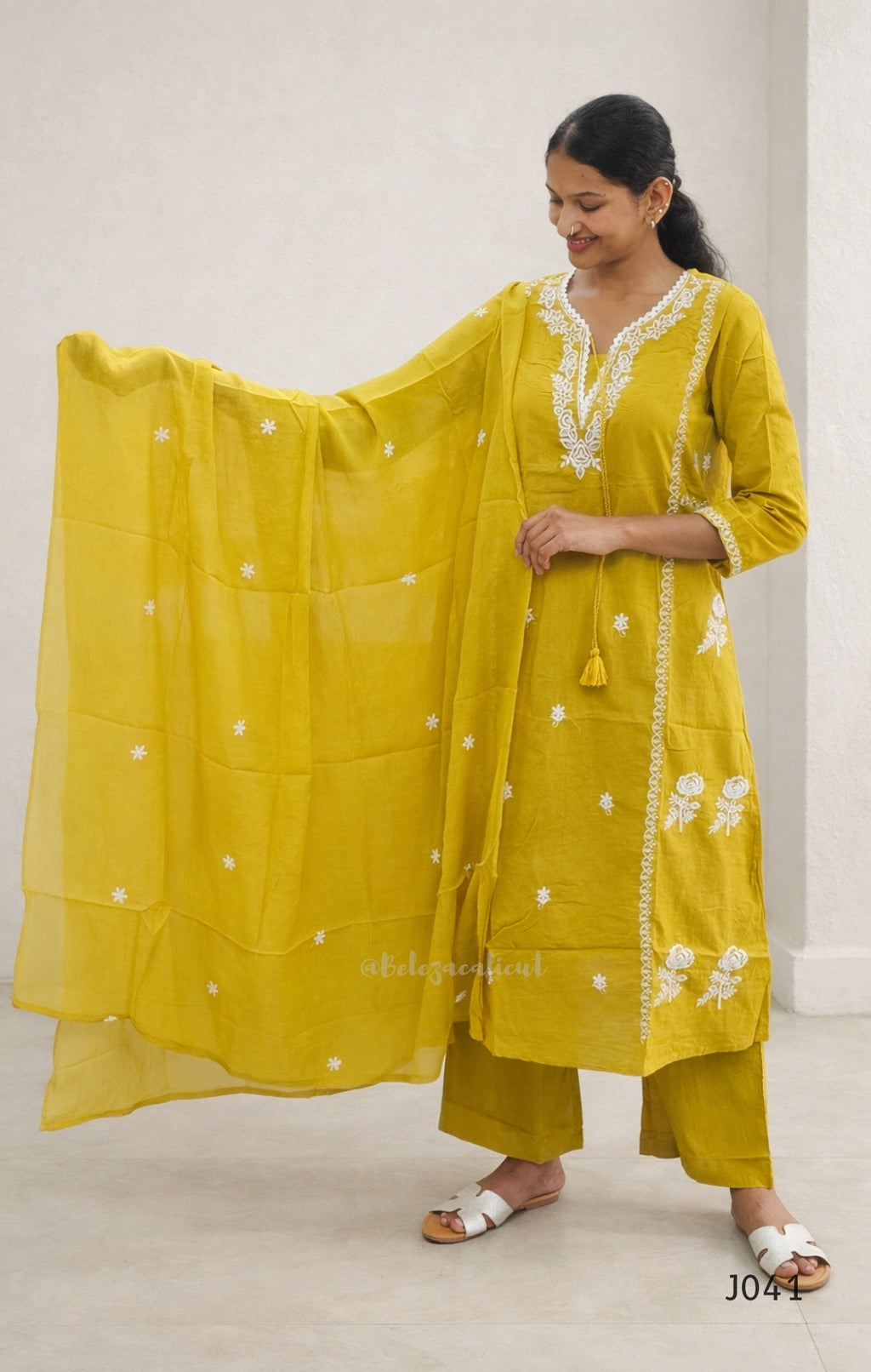 Woman wearing a yellow traditional outfit with a matching dupatta on a plain background