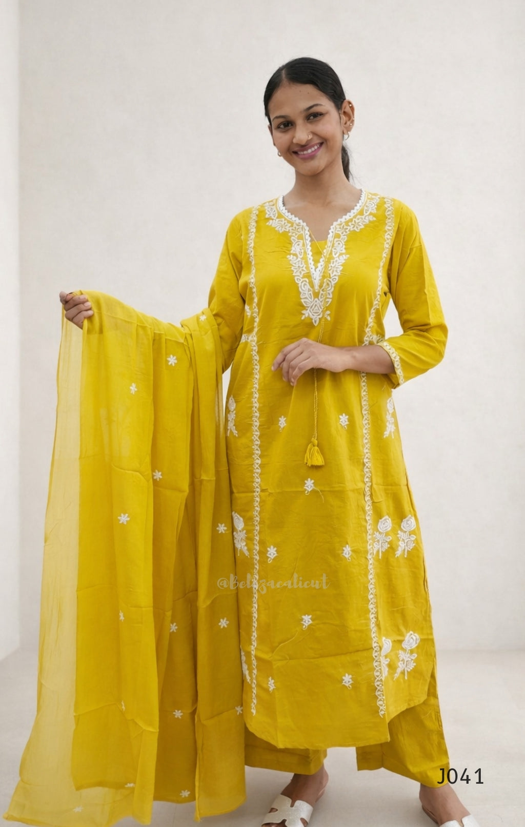 Woman wearing a yellow traditional outfit with white embroidery on a white background