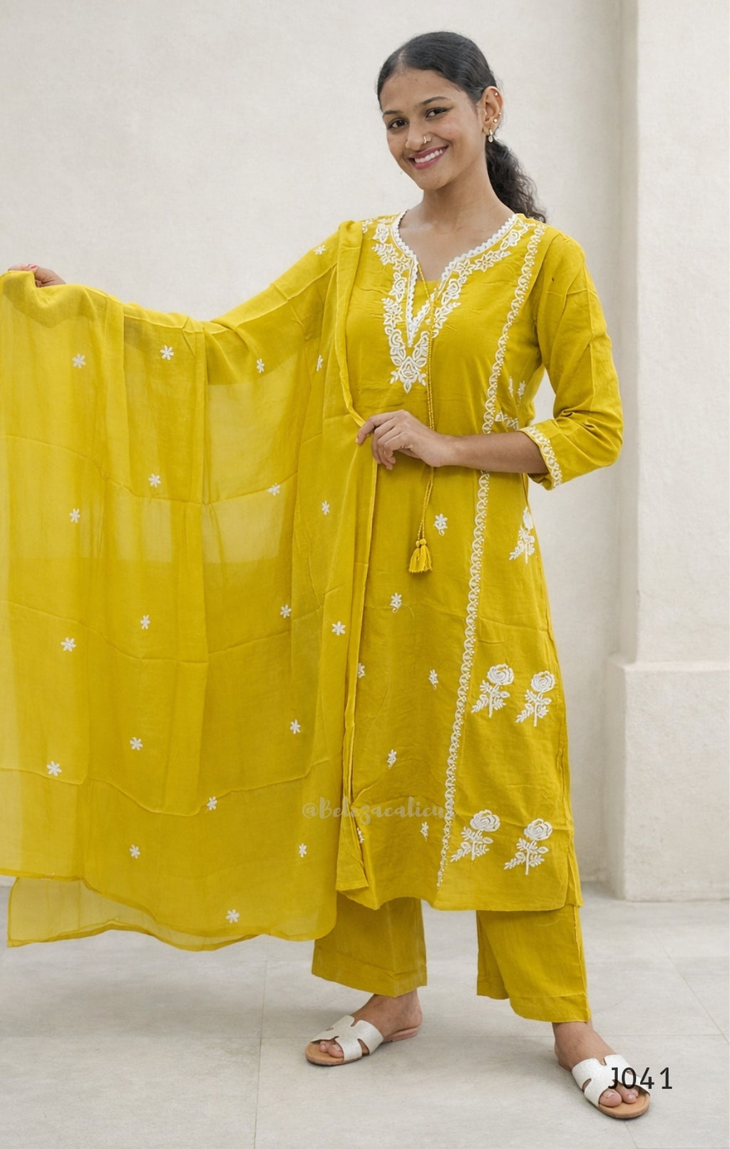 Woman wearing a yellow traditional outfit with white embroidery against a white background