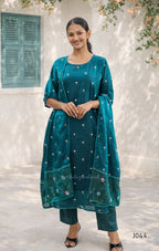 Woman wearing a teal traditional outfit with a matching dupatta in an outdoor setting.