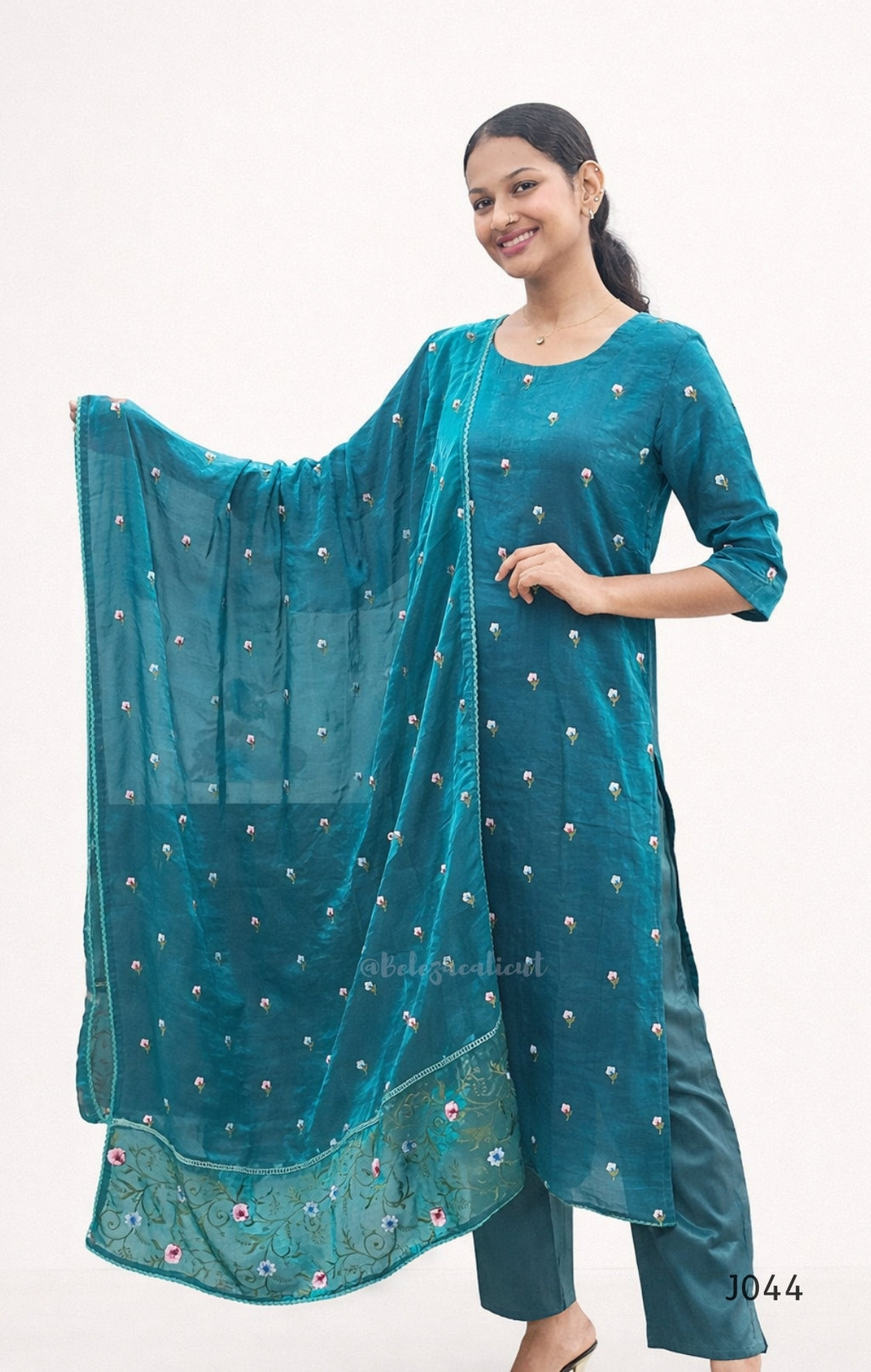 Woman wearing a teal traditional outfit with a matching dupatta on a white background
