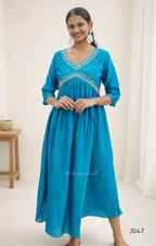 Woman wearing a blue dress with intricate detailing on a white background