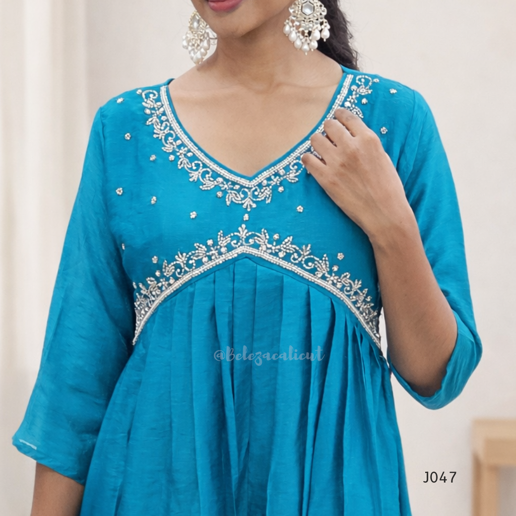 Teal dress with white embroidery on a plain background
