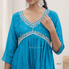 Teal dress with white embroidery on a plain background