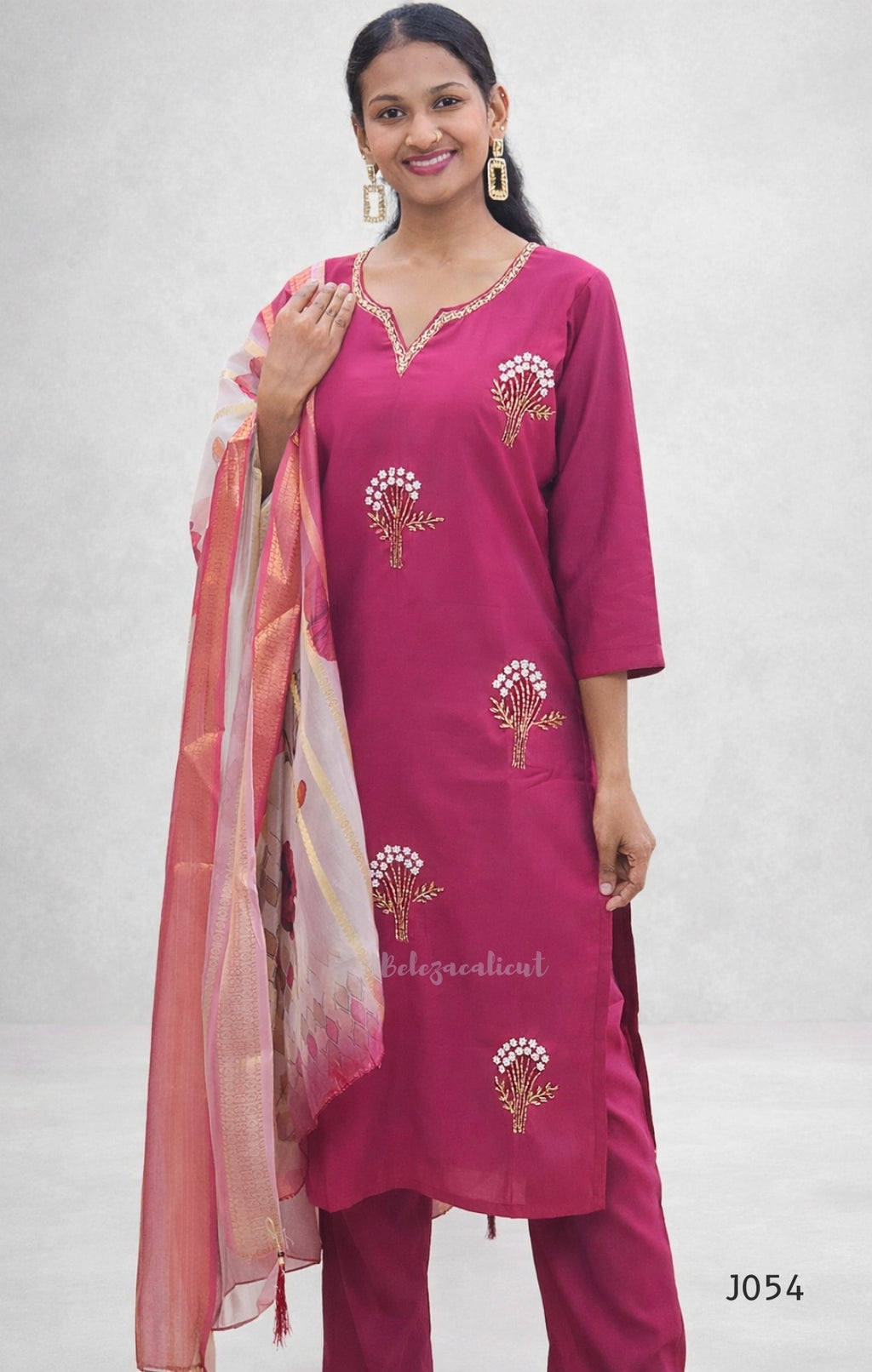 Woman wearing a pink traditional outfit with embroidery on a white background