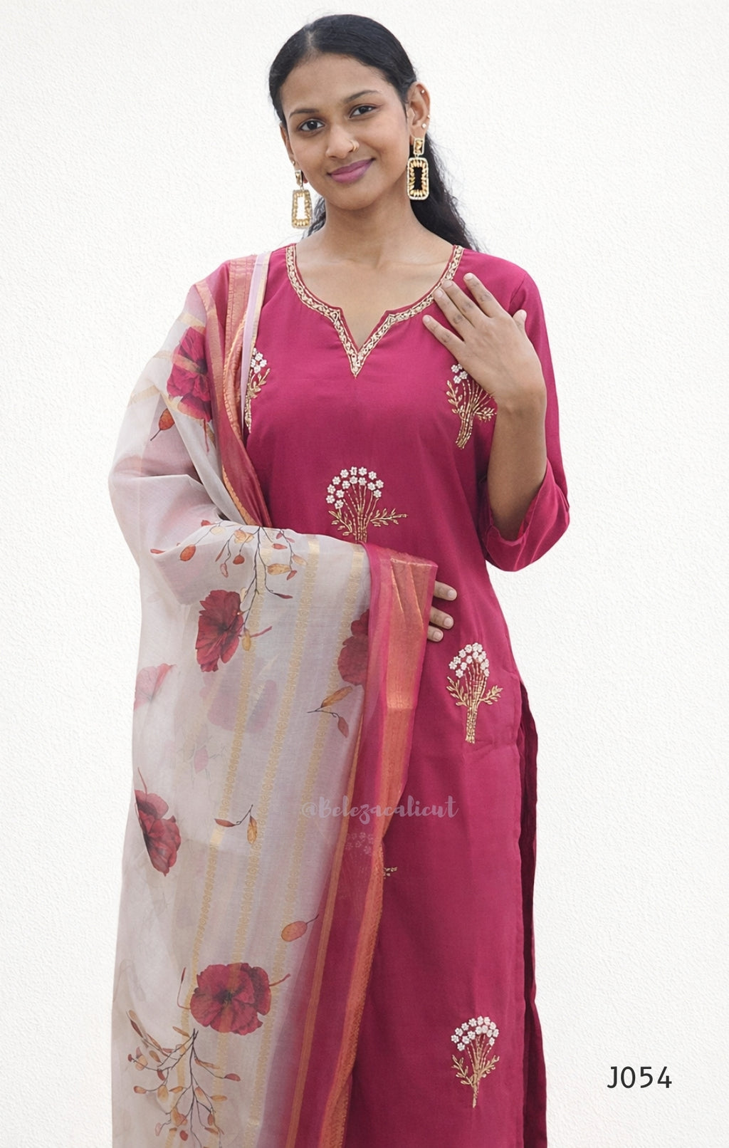 Woman wearing a pink embroidered kurta with a floral dupatta on a white background