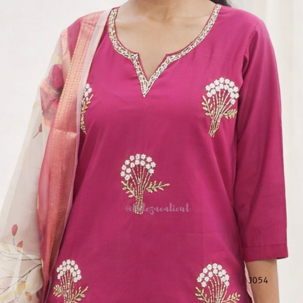Pink traditional outfit with floral embroidery on a plain background