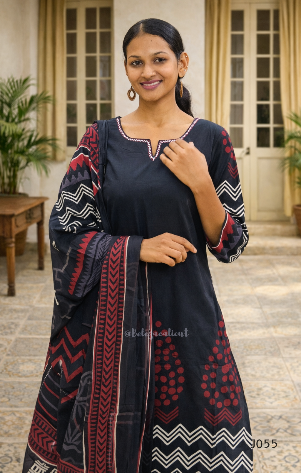 Woman wearing a black and red patterned traditional outfit in an outdoor setting.