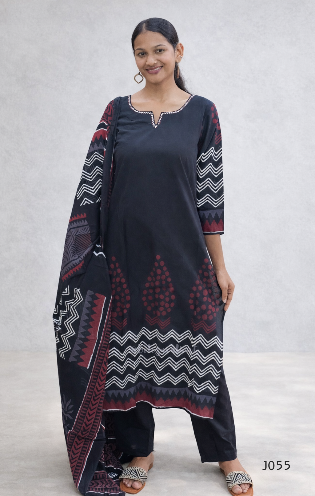 Woman wearing a dark blue kurta with patterned sleeves and pants on a light gray background