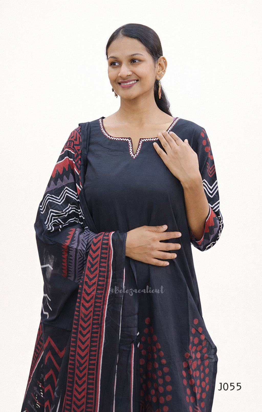 Woman wearing a black dress with red and white patterns on a white background
