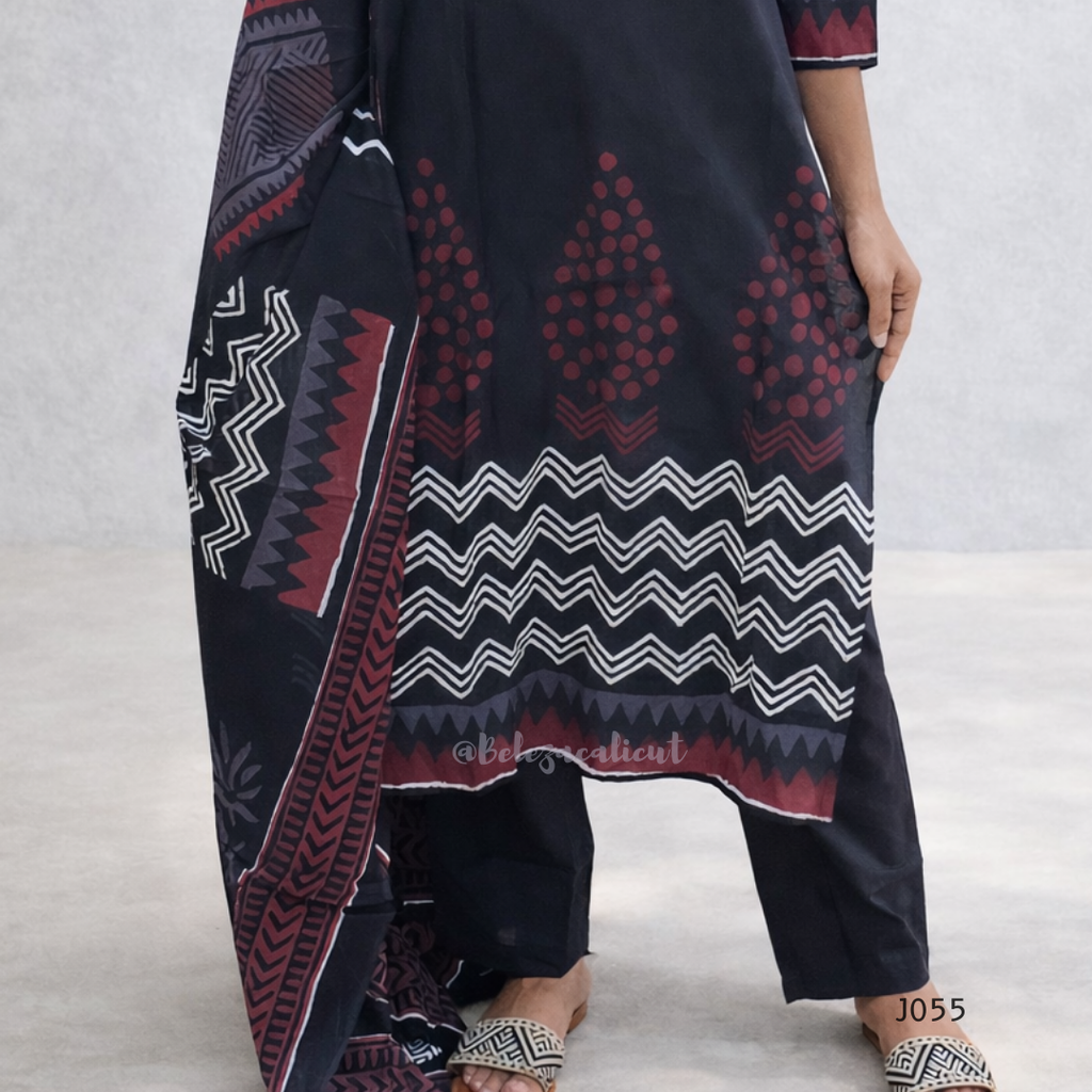 Person wearing a dark blue patterned dress with red and white designs on a light gray background