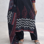 Person wearing a dark blue patterned dress with red and white designs on a light gray background