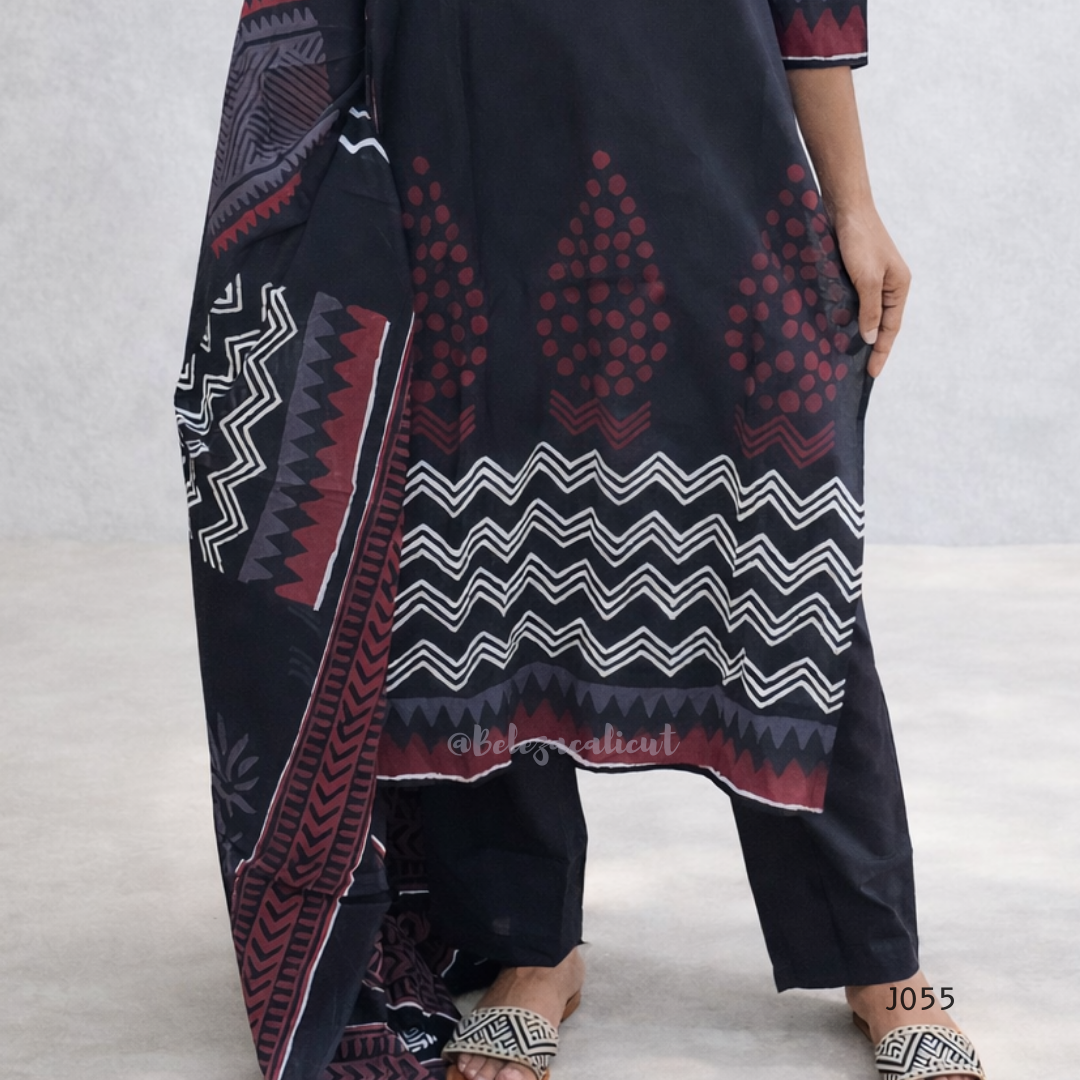 Person wearing a dark blue patterned dress with red and white designs on a light gray background