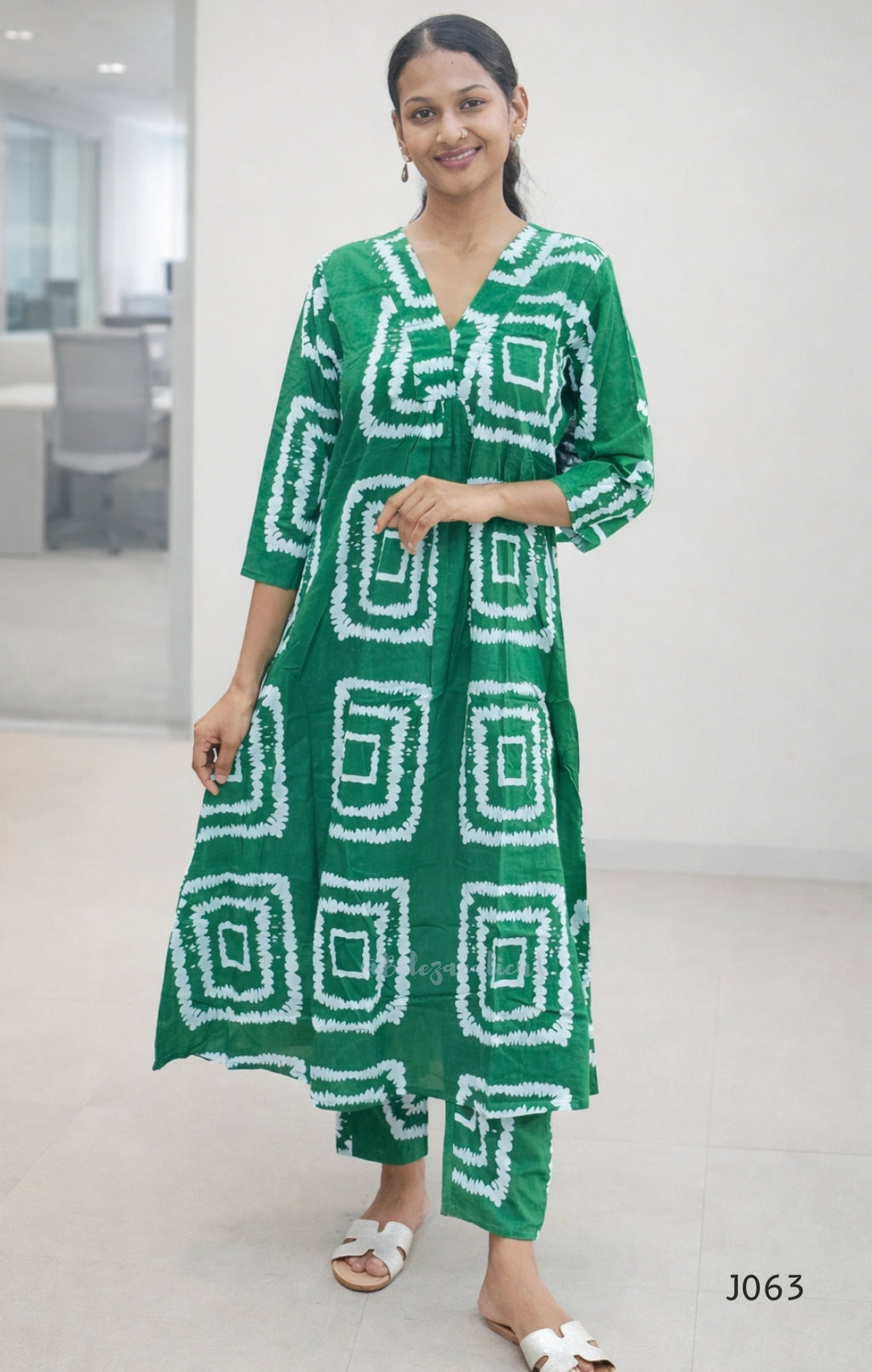Woman wearing a green and white patterned dress in an indoor setting
