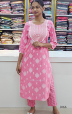 Woman wearing a pink traditional outfit with white patterns in a store setting.