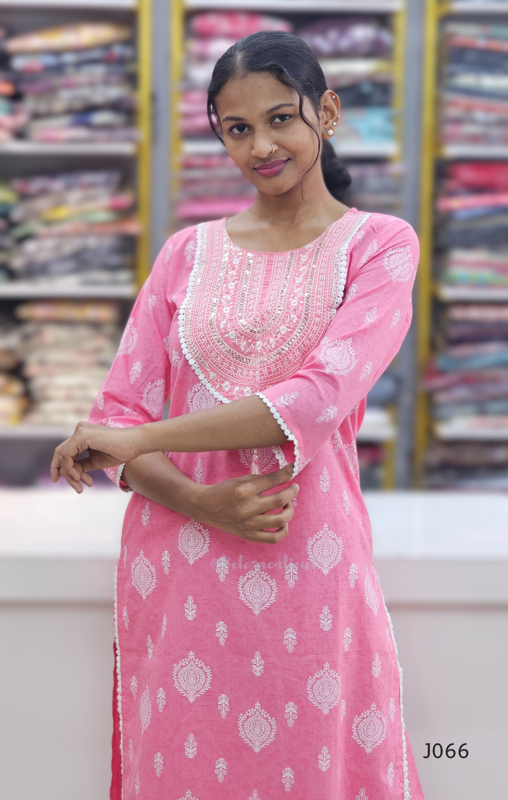 Woman wearing a pink traditional outfit with white patterns in a store setting