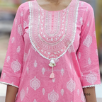 Pink traditional outfit with white embroidery and a tassel detail on a blurred background