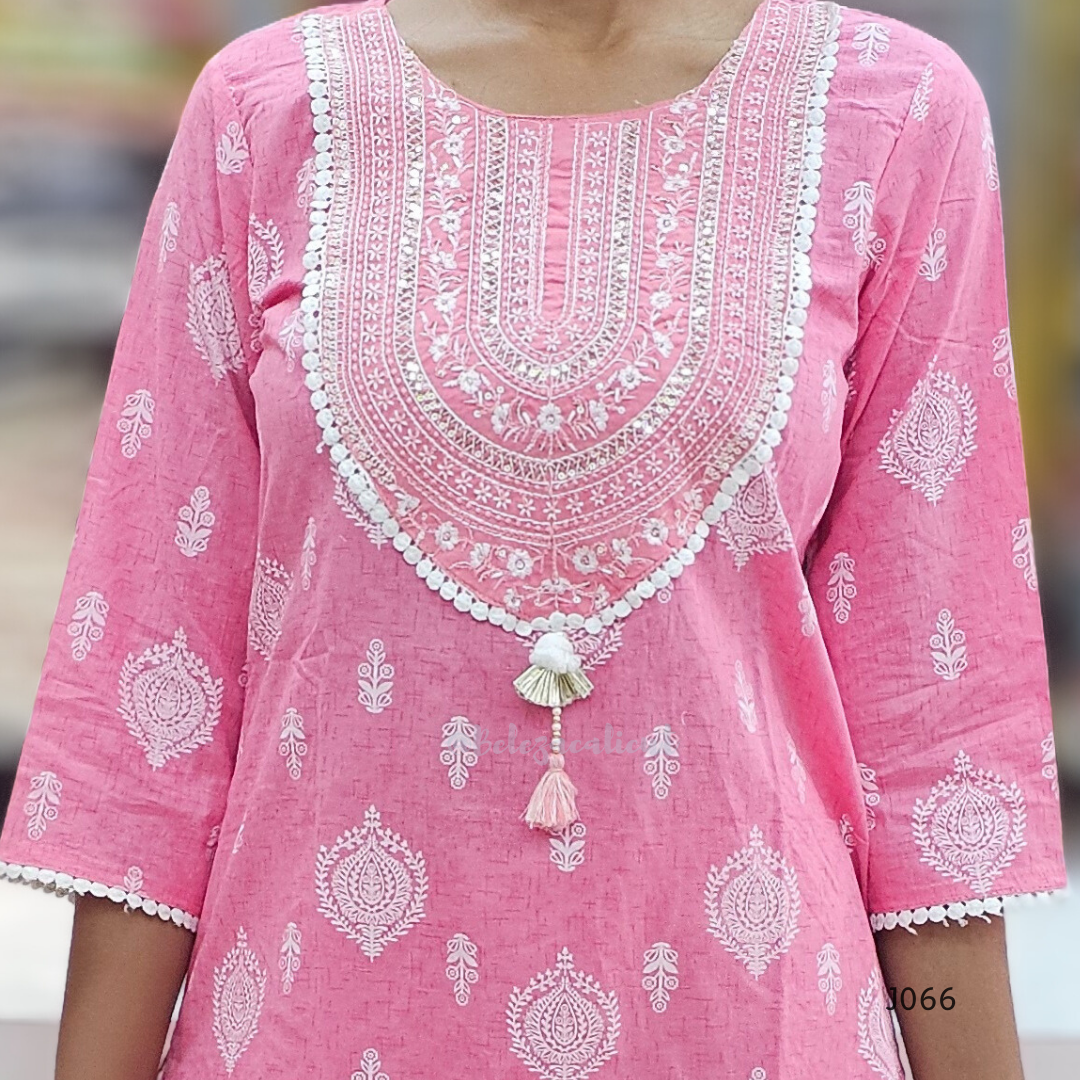 Pink traditional outfit with white embroidery and a tassel detail on a blurred background