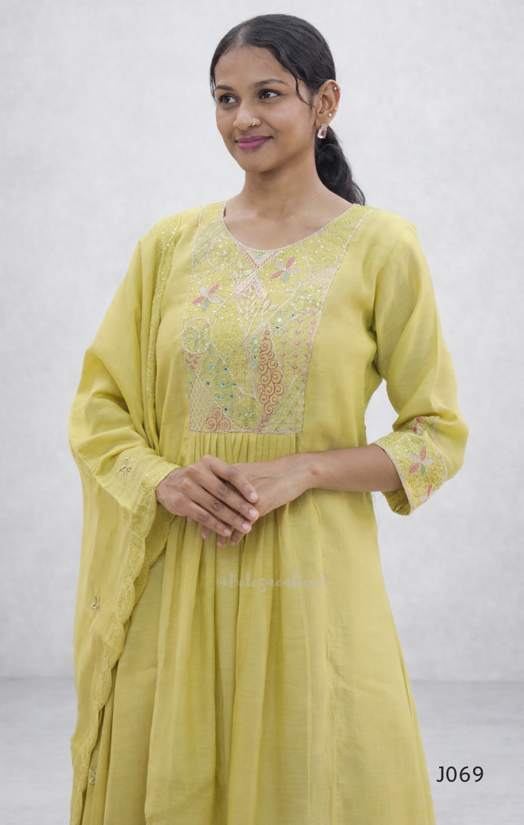 Woman wearing a light green kurta with floral embroidery on a plain background
