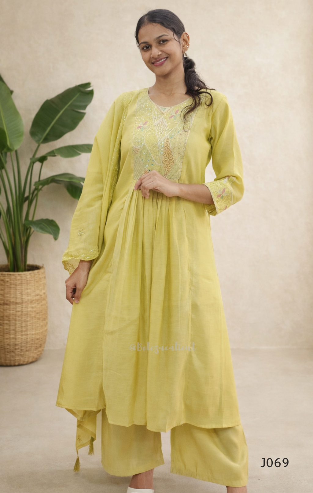 Woman wearing a light green traditional outfit with a plant in the background